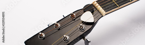 Close up view of guitar picks under strings on white background, panoramic shot
