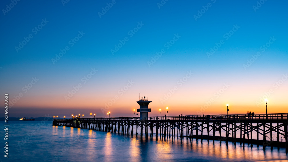 Beautiful Seal Beach Pier at sunset; peaceful water and wooden bridge