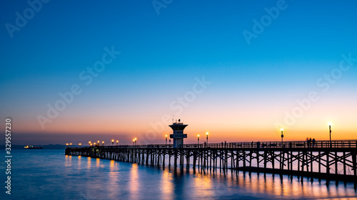 Beautiful Seal Beach Pier at sunset; peaceful water and wooden bridge