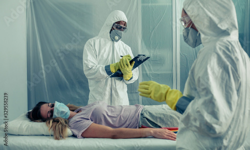 Tablou pe pânză Doctors with bacteriological protection suits examining a patient