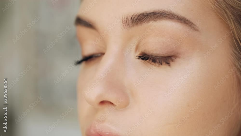 A close-up view of woman's eyes while a hand of makeup artist is applying makeup at a beauty salon A close-up view of woman's eyes while a hand of makeup artist is applying makeup at a beauty salon