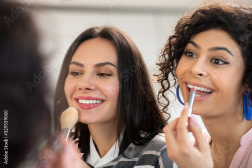 Two dark-haired women doing make up and feeling great