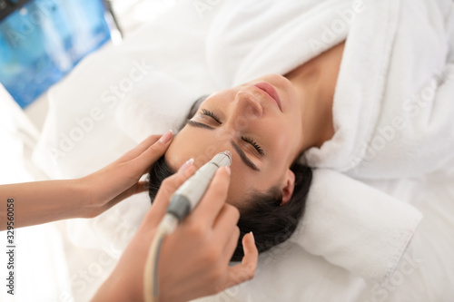 Dark-haired woman laying on the couch feeling relaxed during beauty procedure