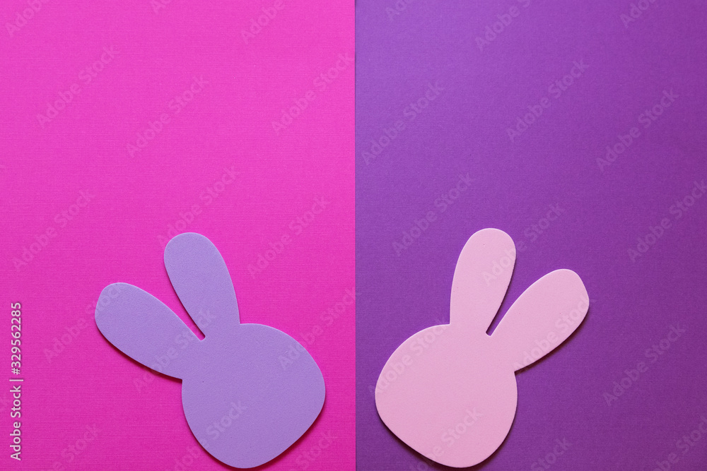 Obraz premium A pink and purple background with pink and purple Easter bunnies. There is room for your text above the bunnies.