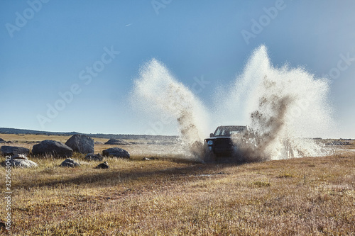 Vehículo todo terreno 4x4 cruzando un badén con agua en forma de charco en el campo. © Trepalio