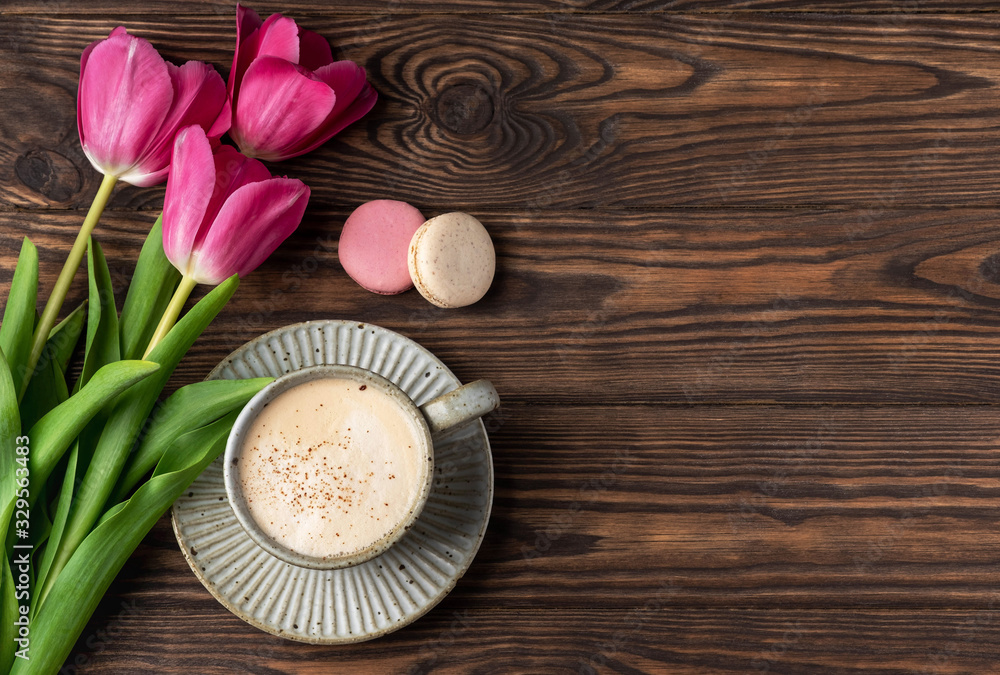 pink tulips, cup with coffee and macaroons on a wooden background, copy space