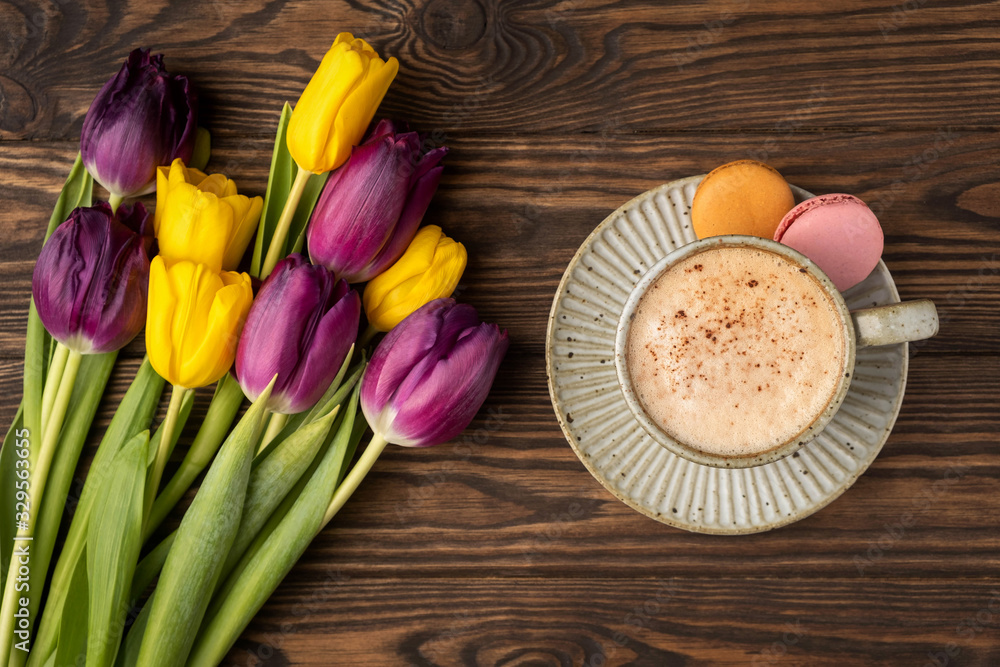 purple and yellow tulips, cup with coffee and macaroon cookies on a wooden background, copy space
