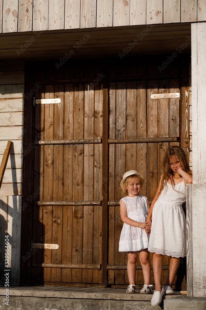 girls hold hands and stand against  wooden door 