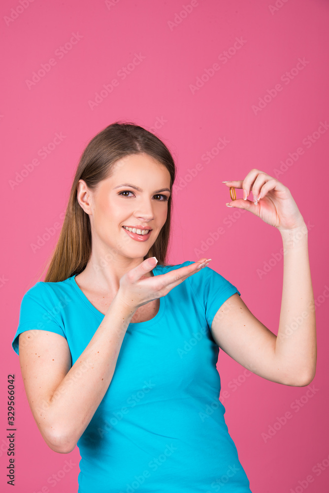 beautiful young woman holding pill or capsule close up isolated on pink background beautiful young woman holding pill or capsule close up isolated on pink background