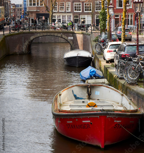Red boat on the Amsterdam canal with a view of a bridge