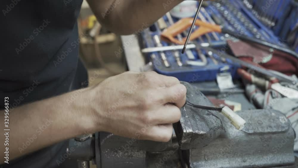 The specialist clamped the item from the car in a vise and repairs The specialist clamped the item from the car in a vise and repairs