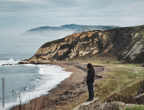 Man stading an looking from a cliff Foggy day Azkorri beach in Getxo Basque Country