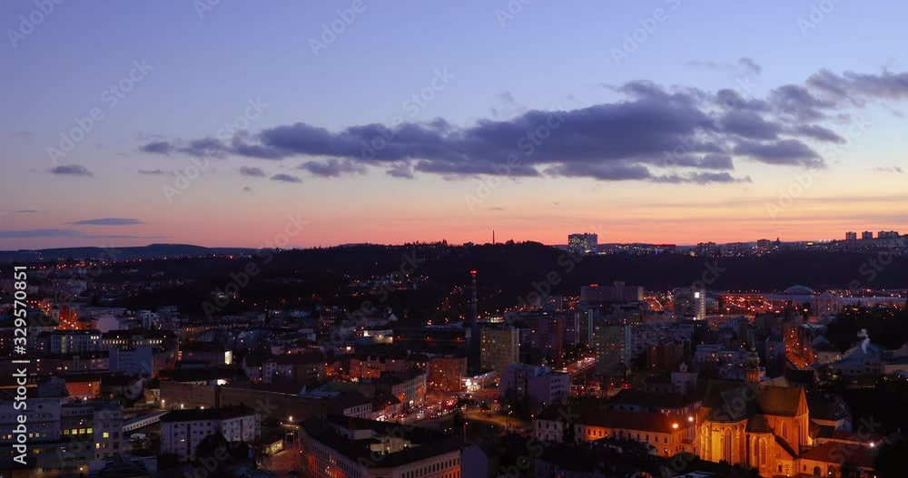 Zoom inside square city street in Brno during sunset covered by cars ride through Mendlovo square with orange clouds on sky and city light which goes on line landscape view captured in 4k 60fps. Zoom inside square city street in Brno during sunset covered by cars ride through Mendlovo square with orange clouds on sky and city light which goes on line landscape view captured in 4k 60fps.