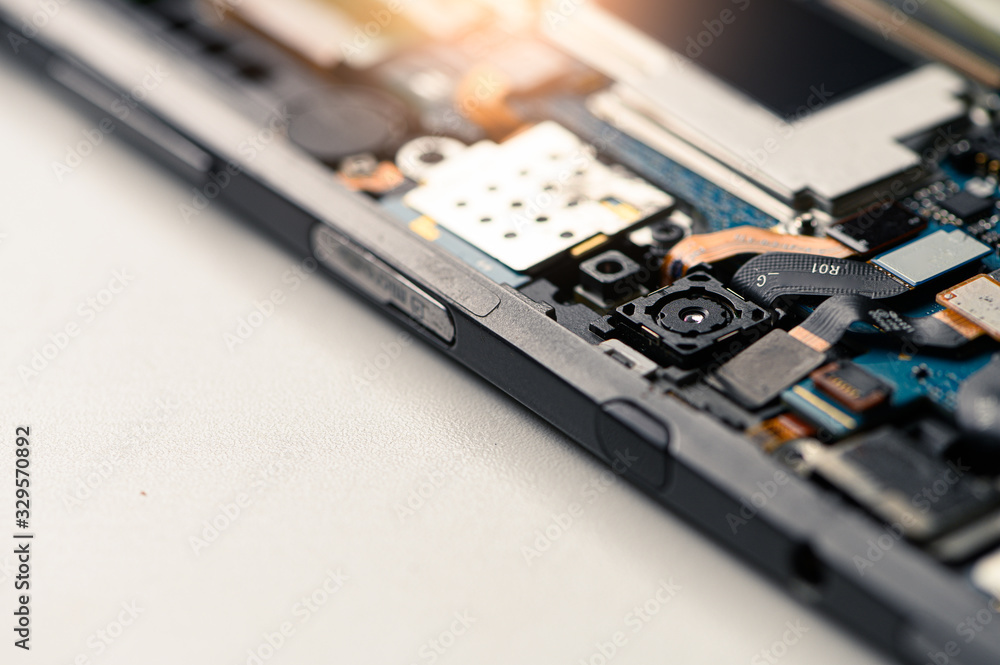 The inside of the smartphone's motherboard and tools lay on the white table. the concept of computer hardware, mobile phone, electronic, repairing, upgrade and technology. The inside of the smartphone's motherboard and tools lay on the white table. the concept of computer hardware, mobile phone, electronic, repairing, upgrade and technology.