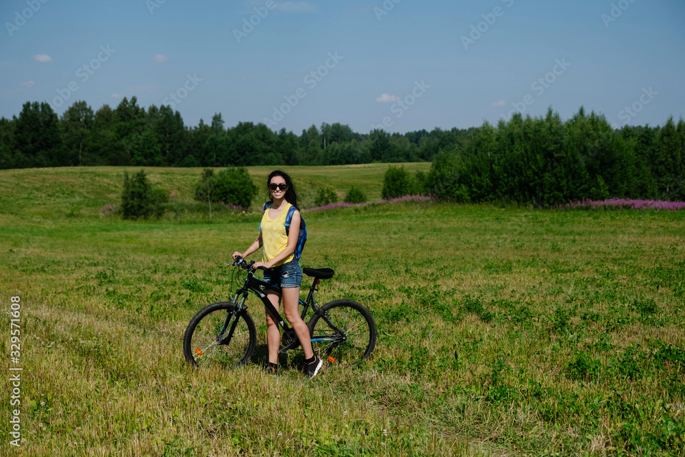 A girl with a Bicycle stands in a field A girl with a Bicycle stands in a field
