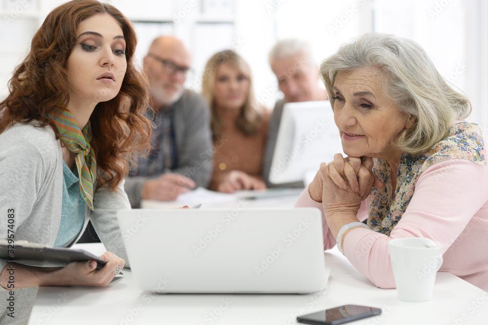 Two senior couples talking with consultant while sitting at table Two senior couples talking with consultant while sitting at table