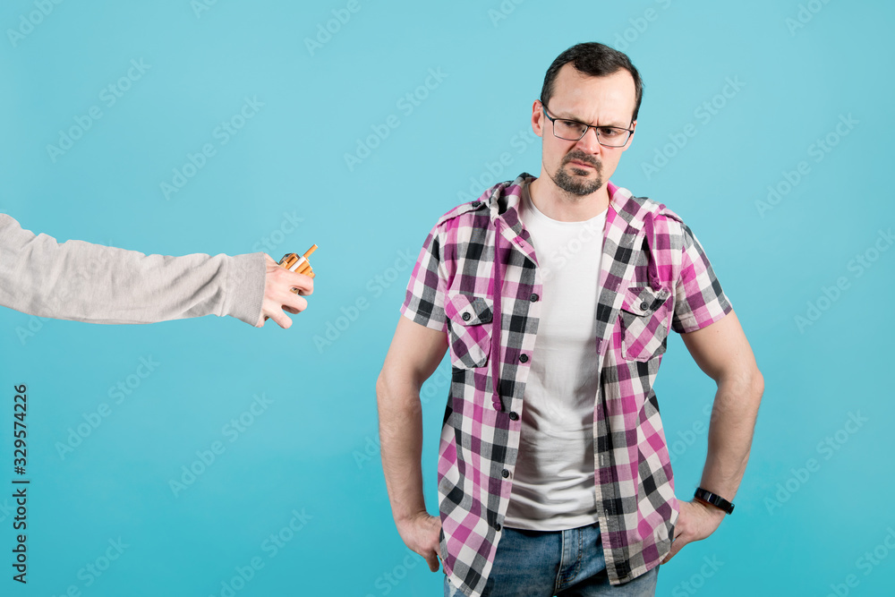 a man with condemnation and anger looks at a pack of cigarettes that another person holds out to him a man with condemnation and anger looks at a pack of cigarettes that another person holds out to him