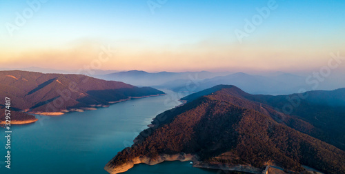 Aerial view of the alpine lake at sunrise in the foggy morning; beautiful mountain and lake scenery