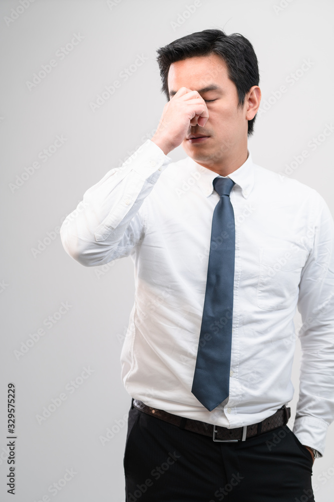 Exhausted Asian worker Squeezing between the eyebrows to try relaxing from hard work shows pain expression face, concept working exhausted, office worker lifestyle, office syndrome, tiring work hour. Exhausted Asian worker Squeezing between the eyebrows to try relaxing from hard work shows pain expression face, concept working exhausted, office worker lifestyle, office syndrome, tiring work hour.