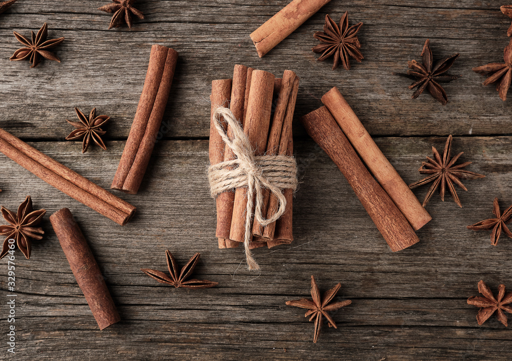 brown cinnamon sticks tied in a bun on a gray wooden background, tasty and fragrant spice brown cinnamon sticks tied in a bun on a gray wooden background, tasty and fragrant spice