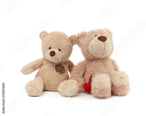 two teddy beige bears sitting huddled together