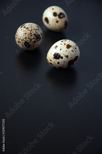 Quail eggs on a black background. Bird spotted eggs. Several objects. Healthy food.