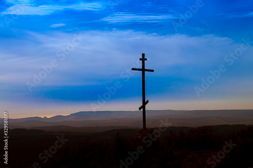 Black religion symbol silhouette Jesus Christ wooden cross on a background with colorful mountain sunset, Easter concept.