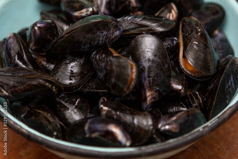 Raw mussels in a blue colander Raw mussels in a blue colander