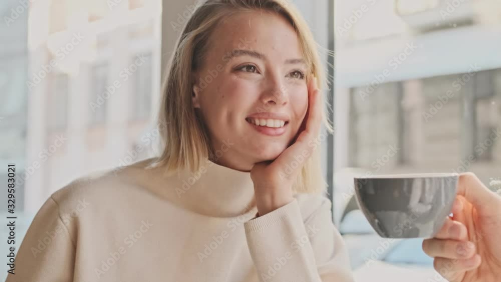 A lovely young couple wearing casual clothes is sitting at the white cafe while having a date A lovely young couple wearing casual clothes is sitting at the white cafe while having a date