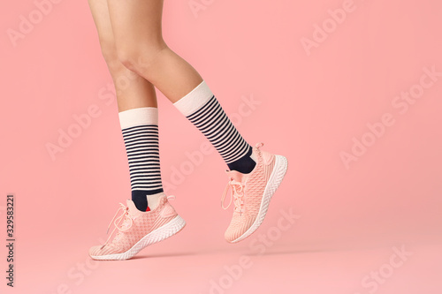 Legs of young woman in socks and shoes on color background