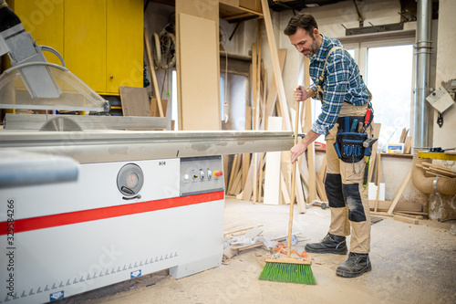 Fotografie Craftsman cleans his carpentry workshop after work
