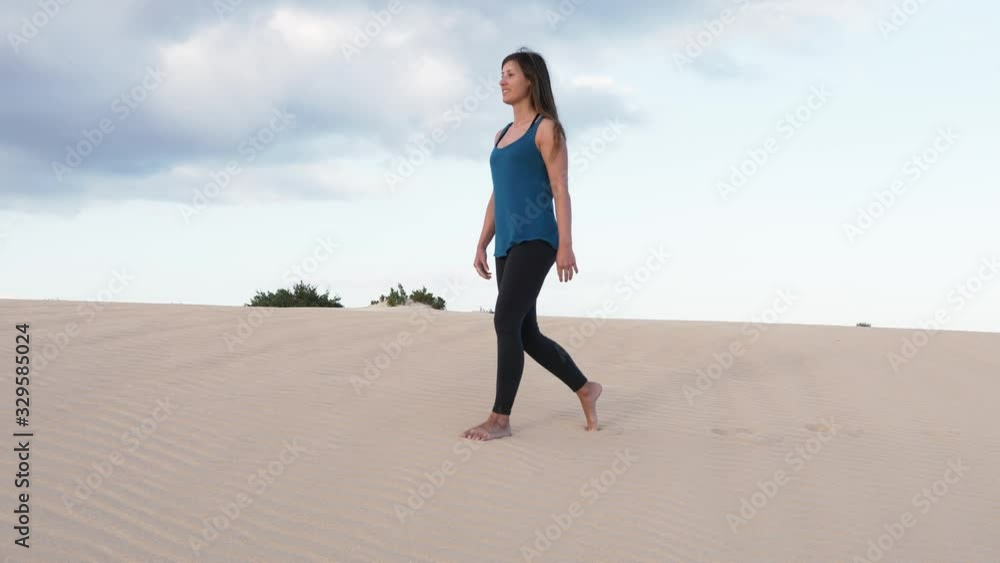 SLOW MOTION Wide to close up gimbal shot of woman walking on desert sand. Girl walking on sand dune bare feet. Summer holiday concept. SLOW MOTION Wide to close up gimbal shot of woman walking on desert sand. Girl walking on sand dune bare feet. Summer holiday concept.