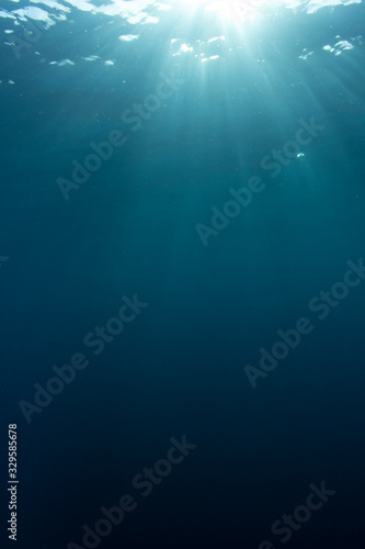 Underwater blue background and sunlight vertical photo 