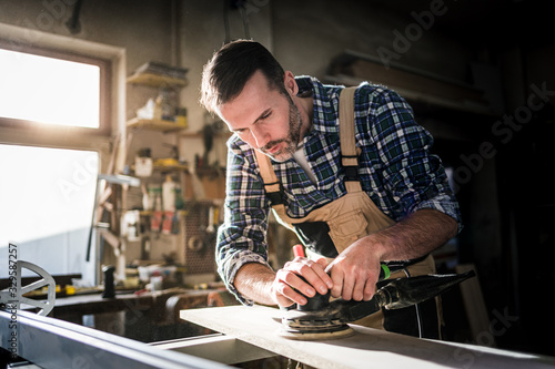 Carpenter working on woodworking in carpentry workshop photo