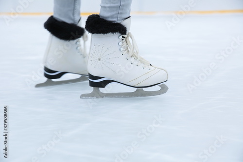 white ice skates is on female legs close up on the ice