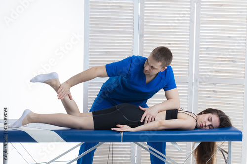 The orthopedic doctor makes a diagnosis of the muscle tone on the girl's legs. Manual therapy
