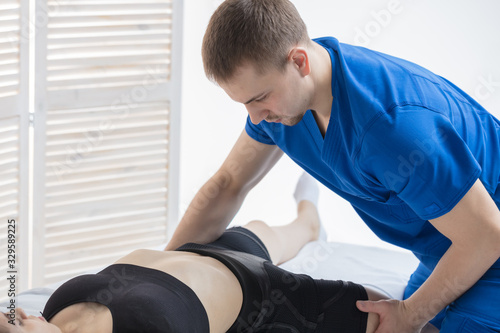 The orthopedic doctor makes a diagnosis of the hip joints for the girl. A chiropractor works
