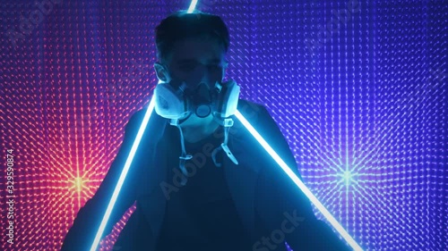 A model guy is dancing in a neon studio in a gas mask. Concept in dubstep style. Air pollution and global warming. Rave party. photo