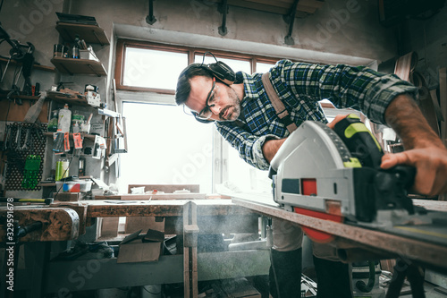 Carpenter using professional circular saw to cutting a wooden board in carpen...