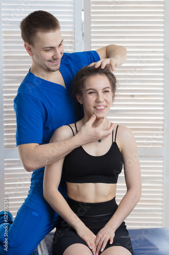 The doctor makes a diagnosis of the head and cervical spine of a young girl. Massage and manual therapy © Abramov Maksim