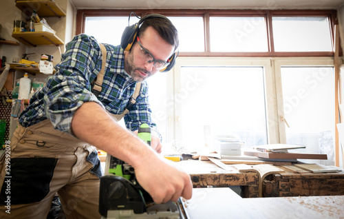 Carpenter using professional circular saw to cutting a wooden board in carpen...