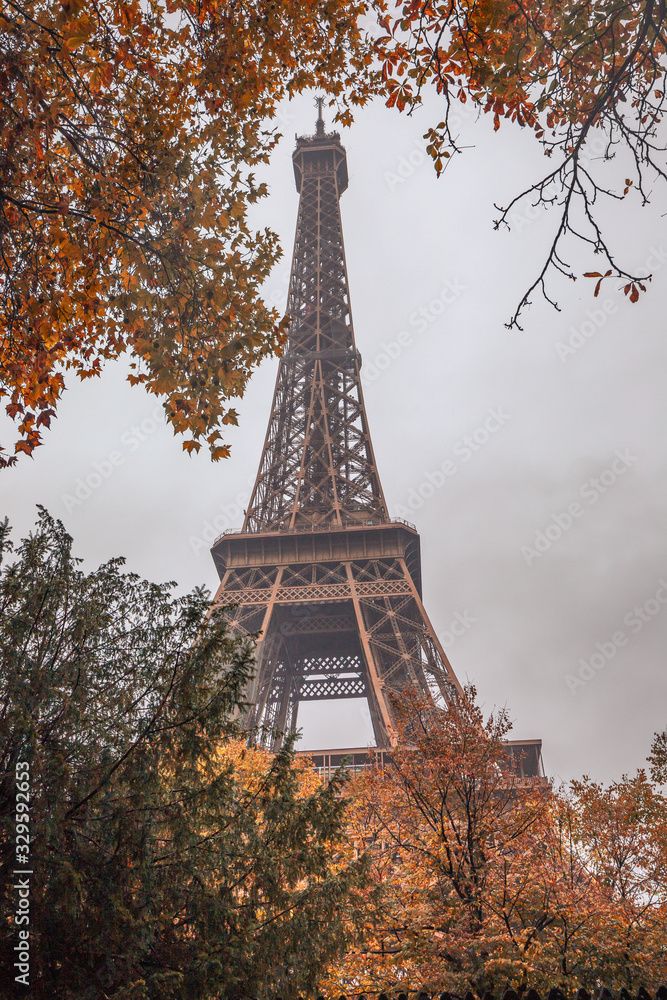 Eiffel tower in Paris France on an autumn day surrounded by brown leaves of trees, tour Eiffel in the fall
