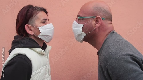 kissing woman and man wearing white health masks defying the virus type coronavirus or covid 19 photo