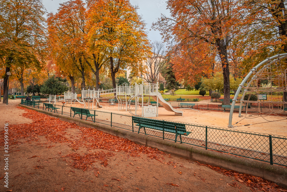 Parisian deserted playground in Autumn with green benches and autumn leaves everywhere Parisian deserted playground in Autumn with green benches and autumn leaves everywhere