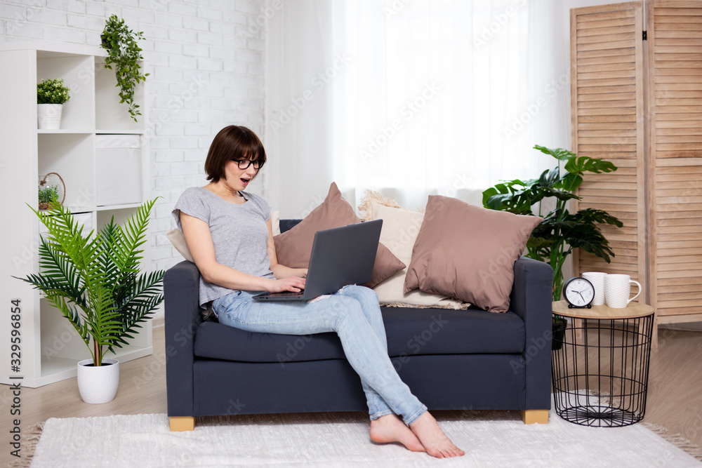 portrait of surprised young woman using laptop in living room portrait of surprised young woman using laptop in living room