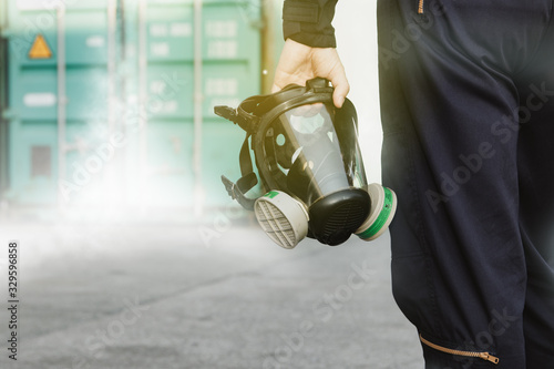 Male industrial technician who holds a respirator mask, an ammonia odor mask, NH3 to control and fix leaks inside the factory's container : Copy Space