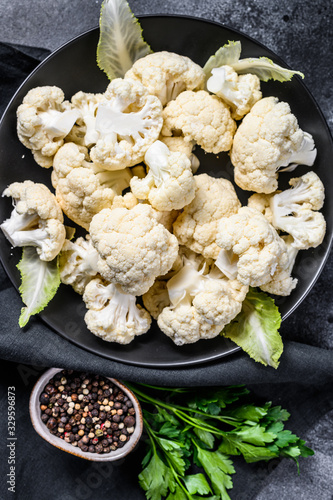 Fresh organic cauliflower cut into small pieces in bowl. Black background. Top view