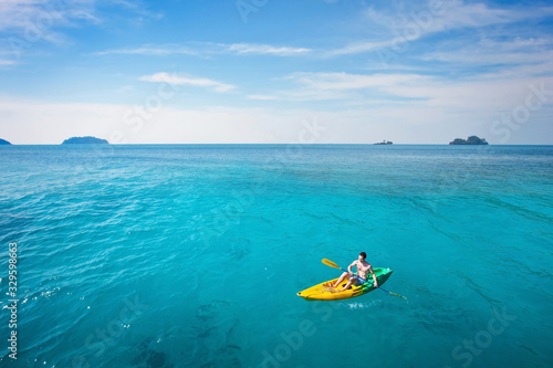 active travel, tourist on kayak paddling on paradise beach in turquoise sea water