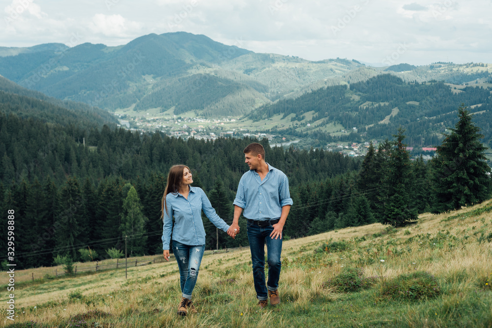 Young couple hike in the mountains. A man and a woman walking and looking at the beautiful landscape.