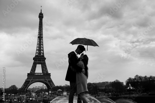 retro view of Paris, couple under umbrella near Eiffel tower, vintage black and white monochrome © Song_about_summer